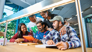 group of students sitting together in library looking at an iPad
