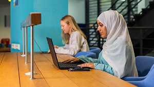 Student sat at desk working on laptop