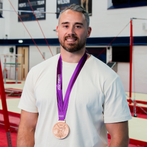 Kristian Thomas photographed wearing a white shirt and an Olympic bronze medal.