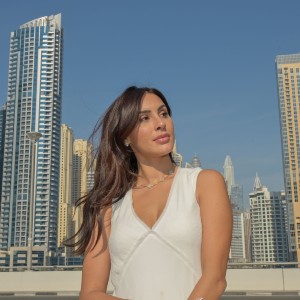 Deana Uppal standing by a railing in front of many tall buildings