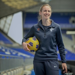 Kerys Harrop in a sports stadium holding a football under her arm