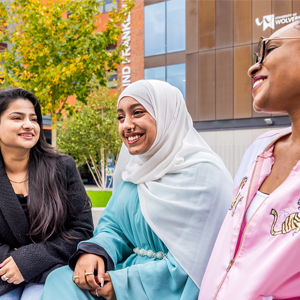a group of global majority students sitting in the courtyard