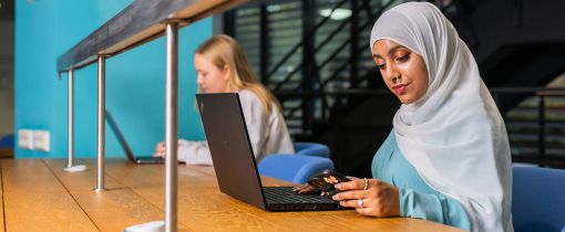 Two female students at desk on laptops